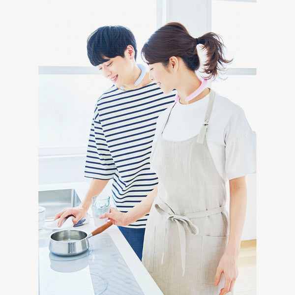 Two people cooking in a bright kitchen, both wearing pastel COOLOOP neck rings.