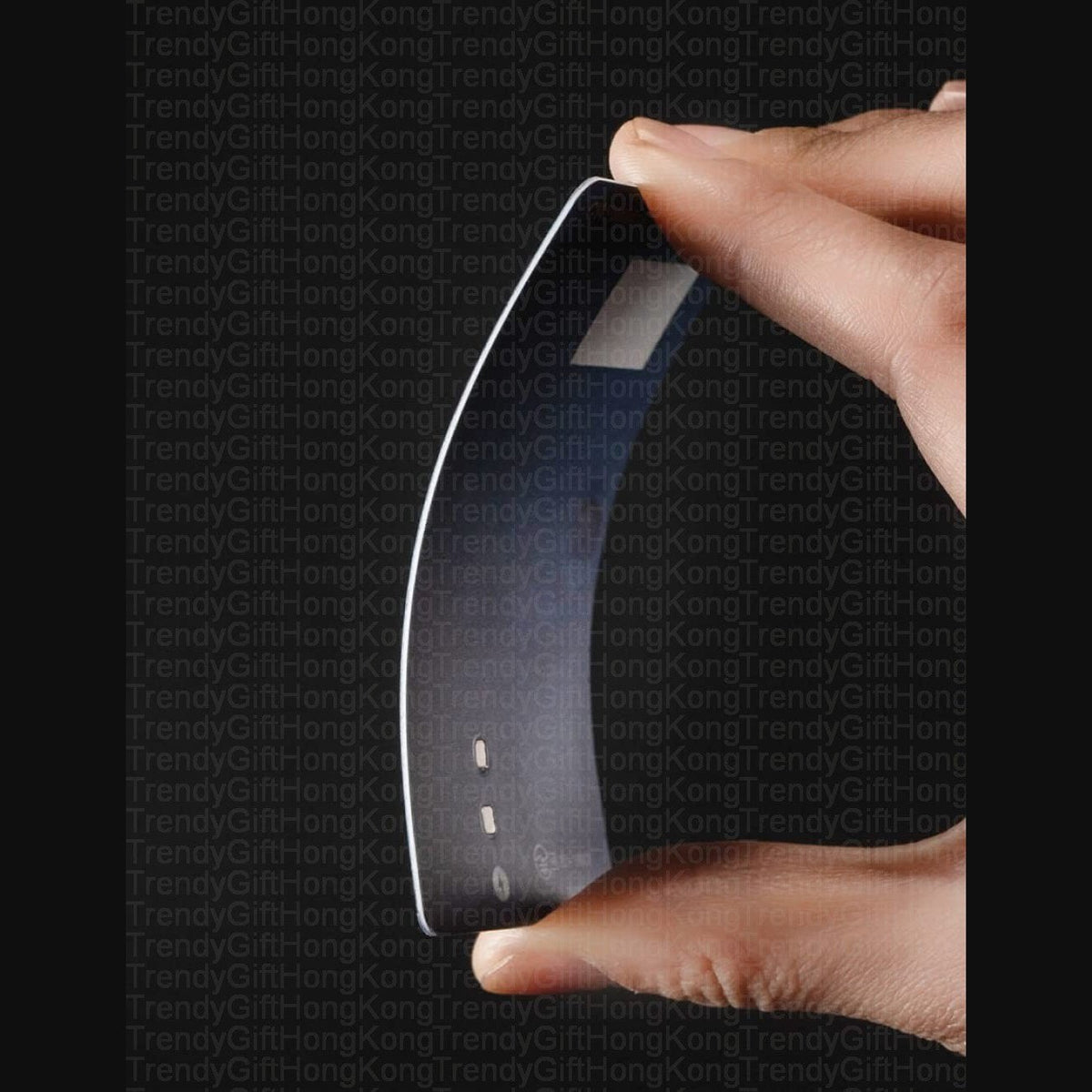 fingers bending a thin black card-shaped device, white border and rectangular surface markings