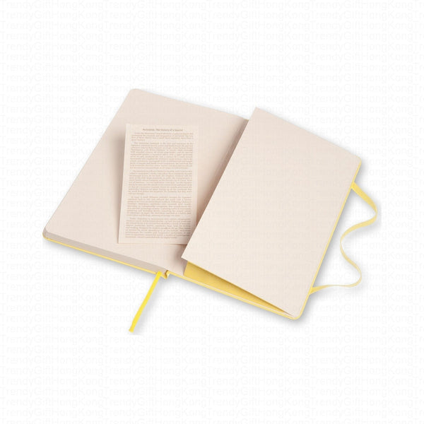 Yellow Moleskine notebook opened with a printed information leaflet